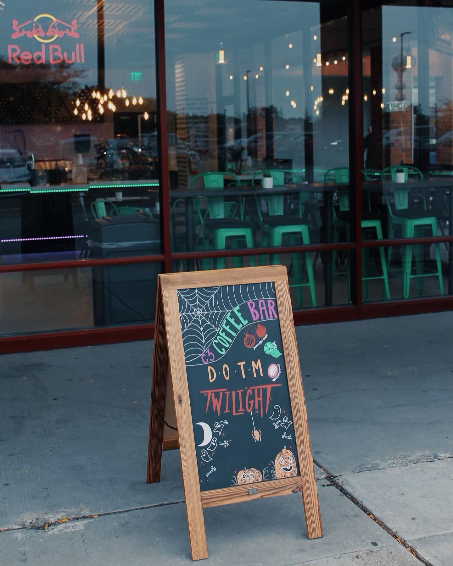 Wooden chalkboard sign in front of a bar, advertising 