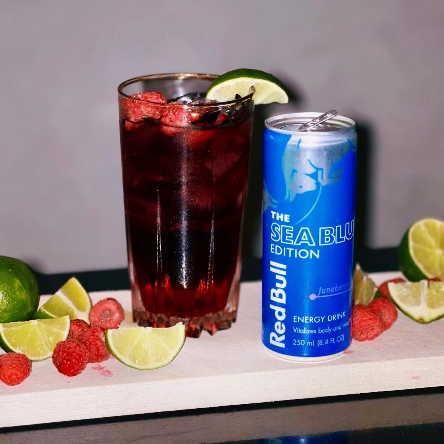 Red Bull Sea Blue Edition drink in a glass with raspberries, lime, and can.