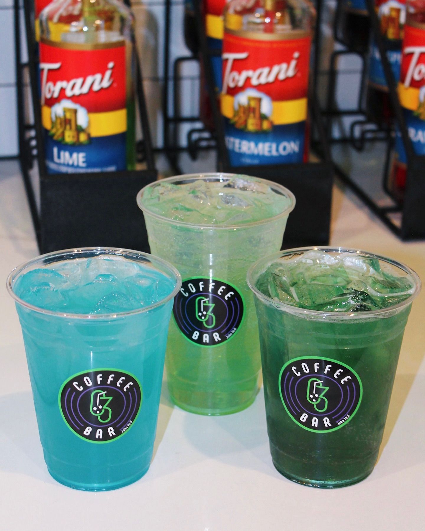 Three colorful sodas in clear cups with a 