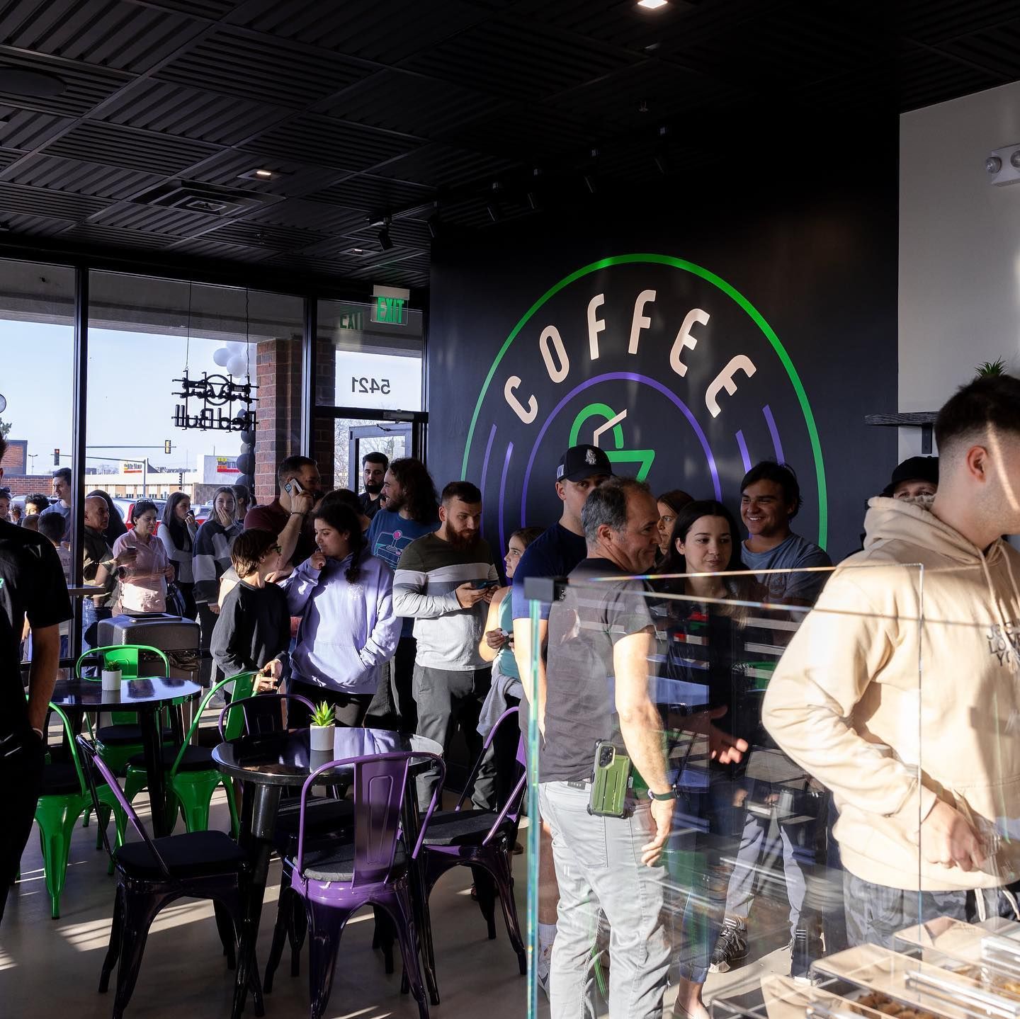 People line up inside a coffee shop with a large 