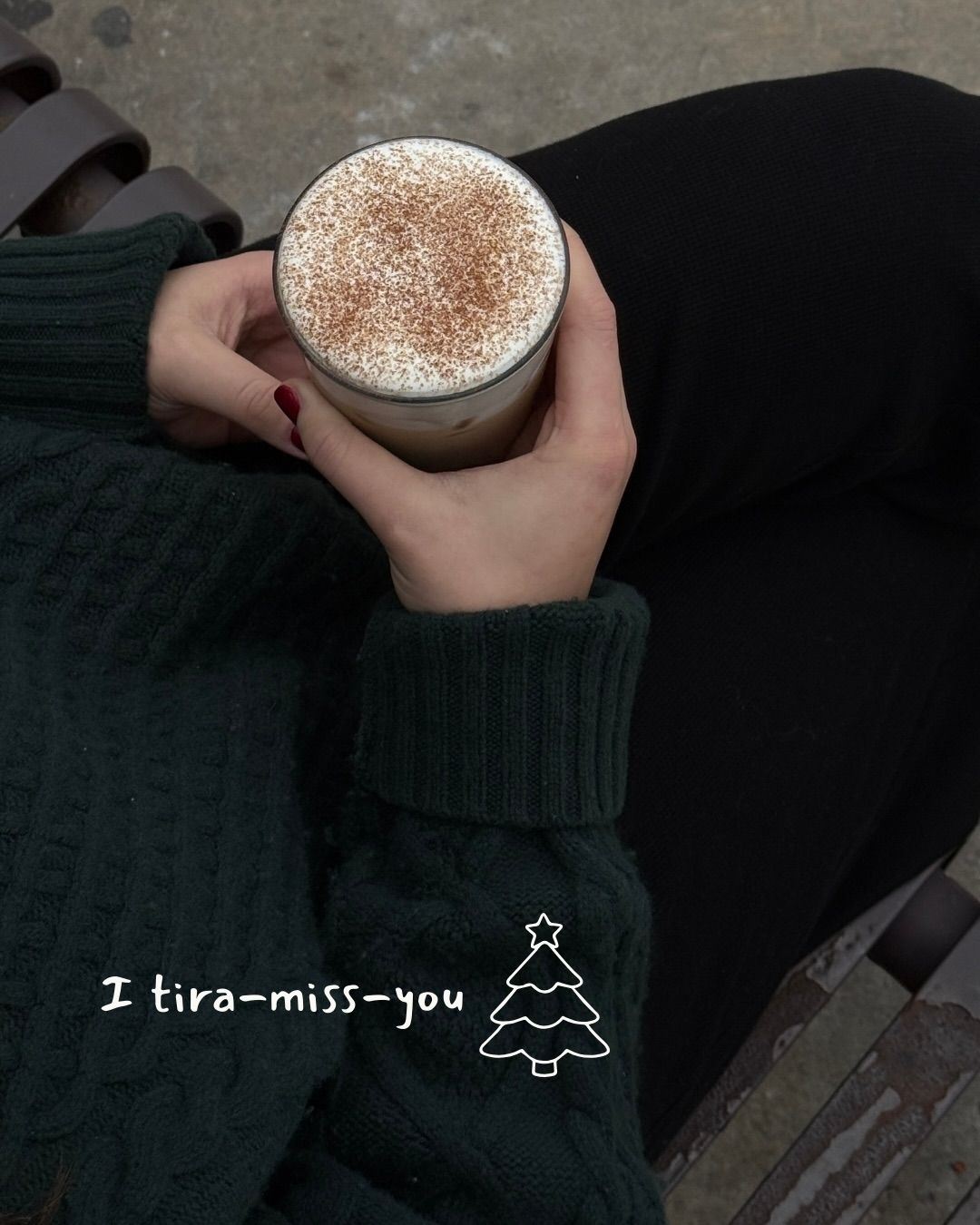 Person holding a drink topped with cinnamon, wearing a green sweater. Text: 