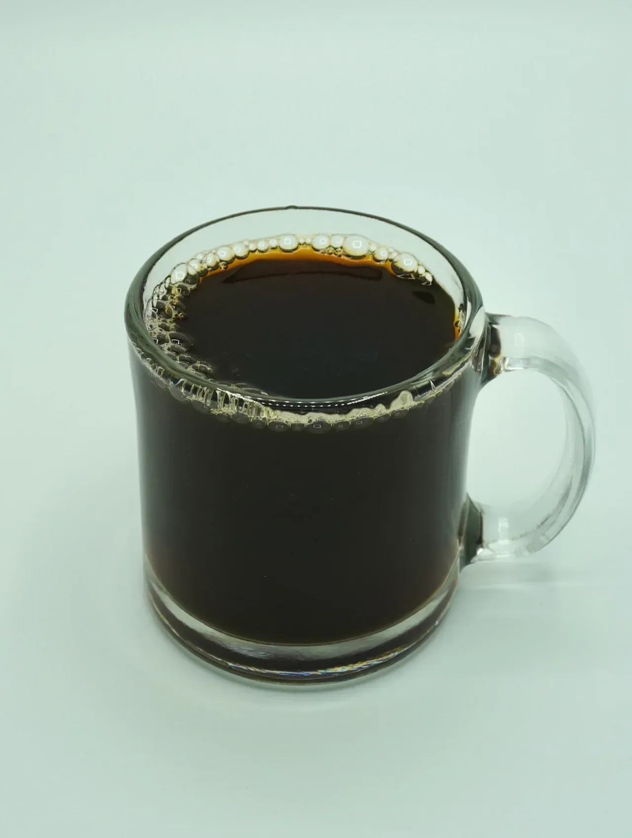 Coffee in a clear glass mug on a white background.