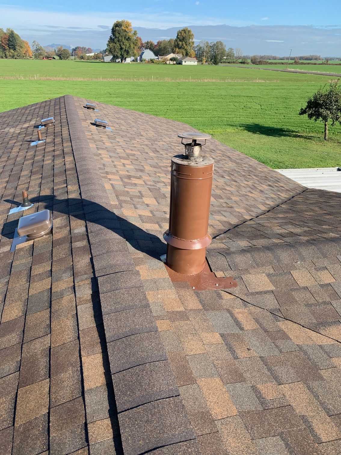 A roof with a chimney on it and a field in the background.