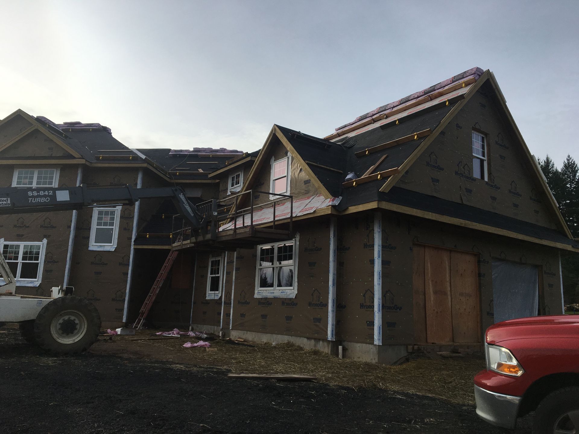 A large house under construction with a red truck parked in front of it