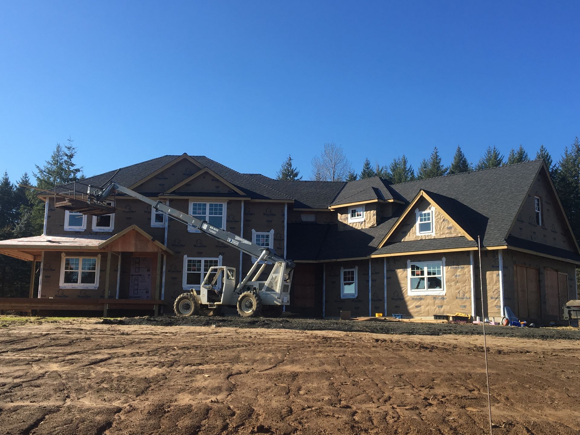 A large house under construction with a tractor in front of it