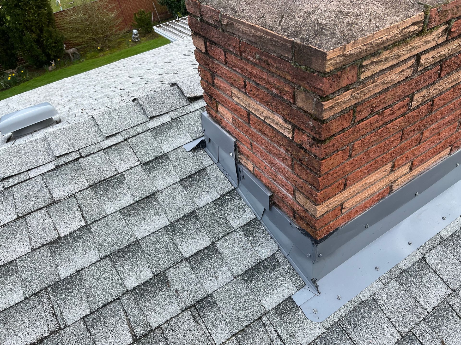 A brick chimney is sitting on top of a roof.