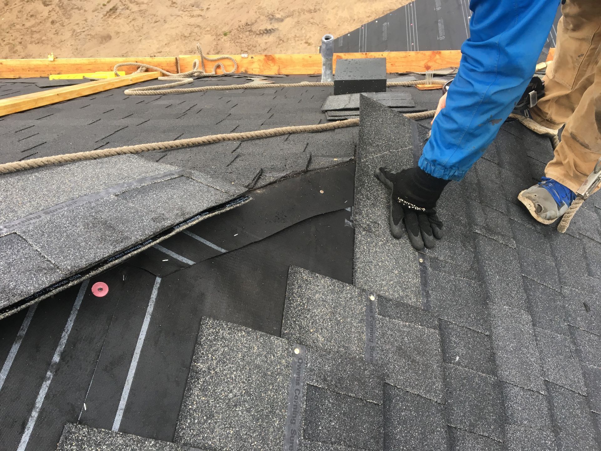A person is laying shingles on a roof.