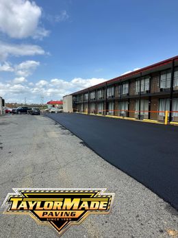 A motel with a lot of parking spaces and a lot of cars parked in front of it.