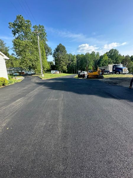 A black asphalt driveway with a yellow truck parked on the side of it.