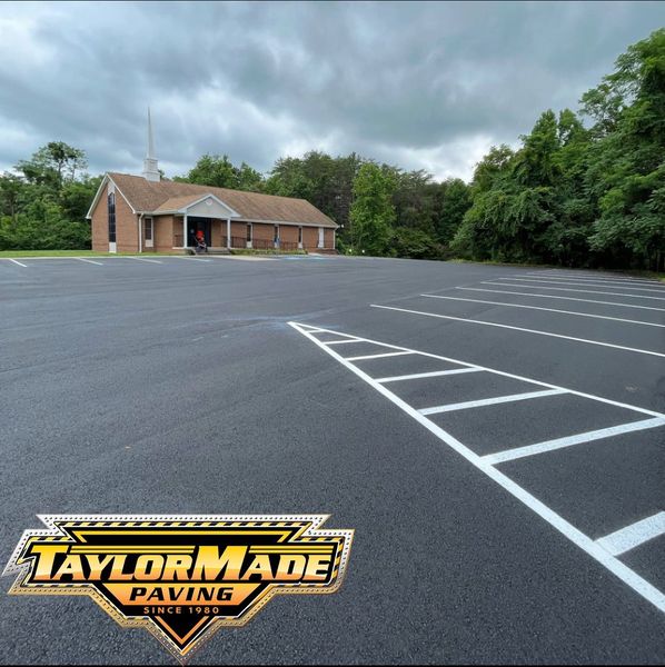 A black asphalt driveway with a yellow truck parked on the side of it.
