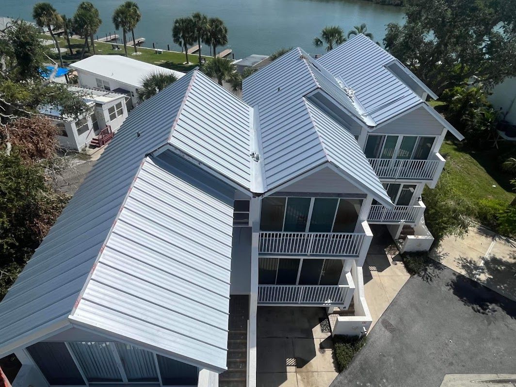 An aerial view of a white house with a metal roof.