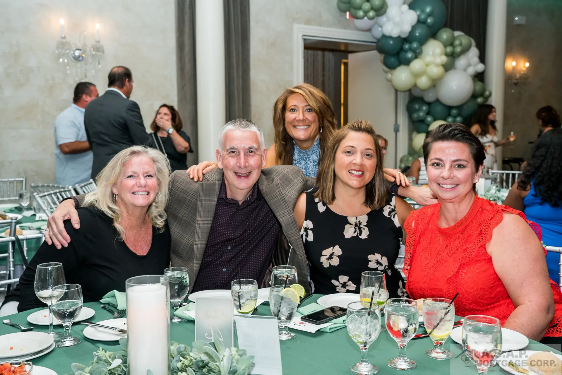 A group of people are posing for a picture at a table at a party.