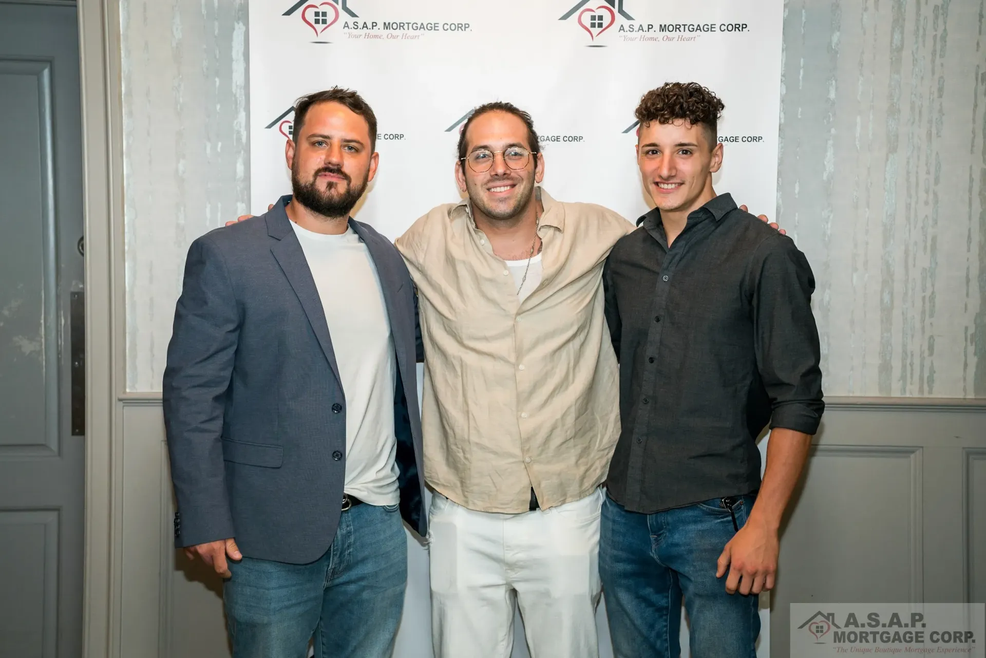 Three men are posing for a picture together in front of a wall.