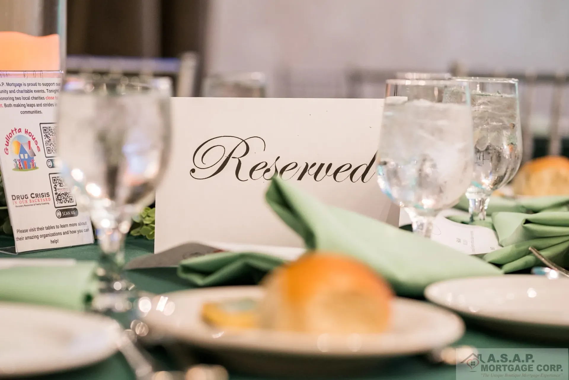 A reserved sign is on a table with plates and glasses.