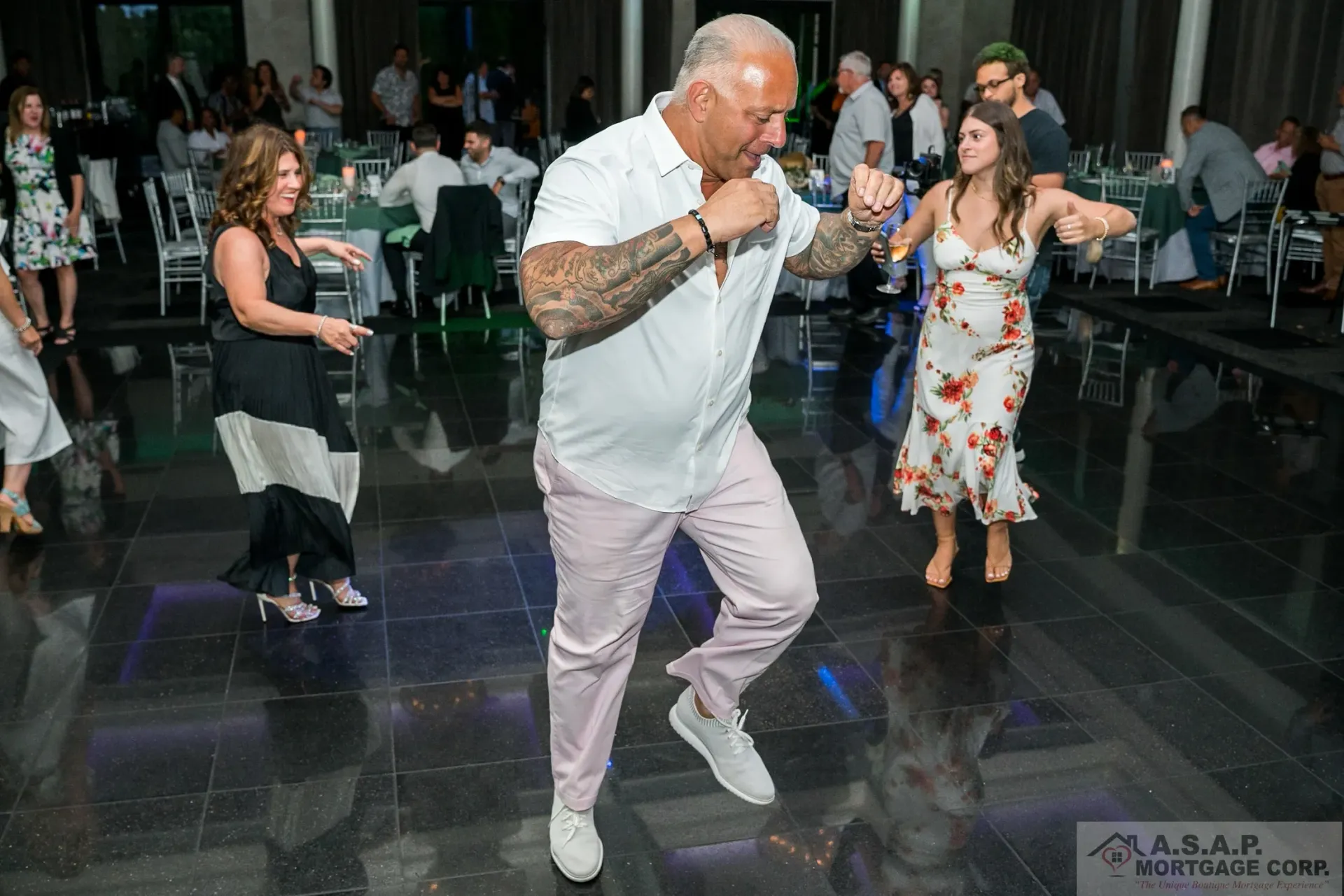 A group of people are dancing on a dance floor at a wedding reception.