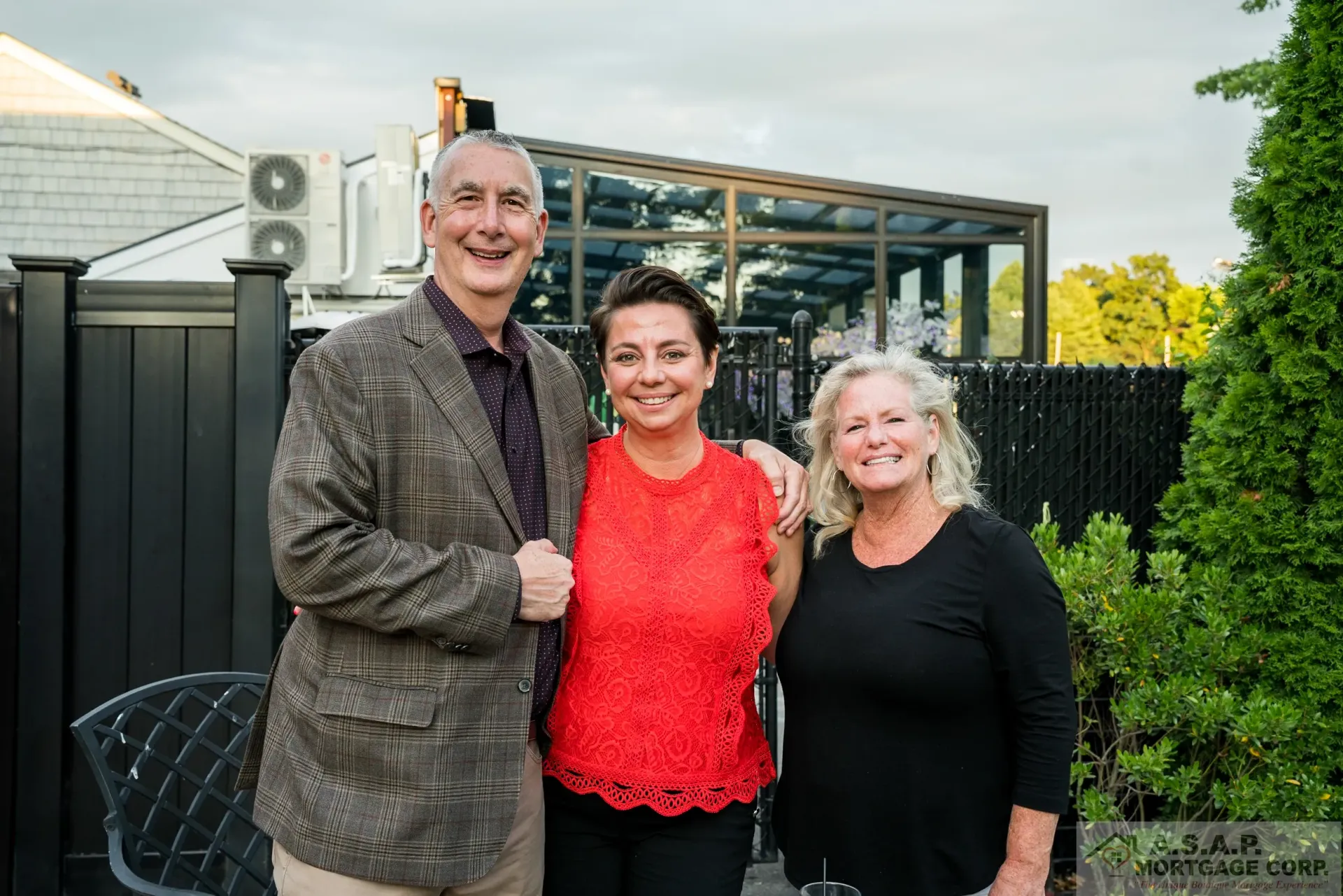 A man and two women are posing for a picture in front of a building.