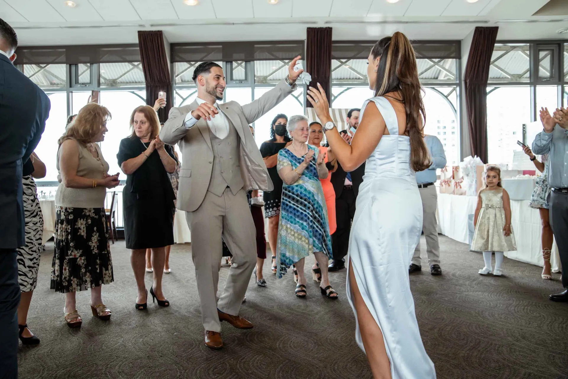 A bride and groom are dancing in front of a crowd of people at a wedding reception.