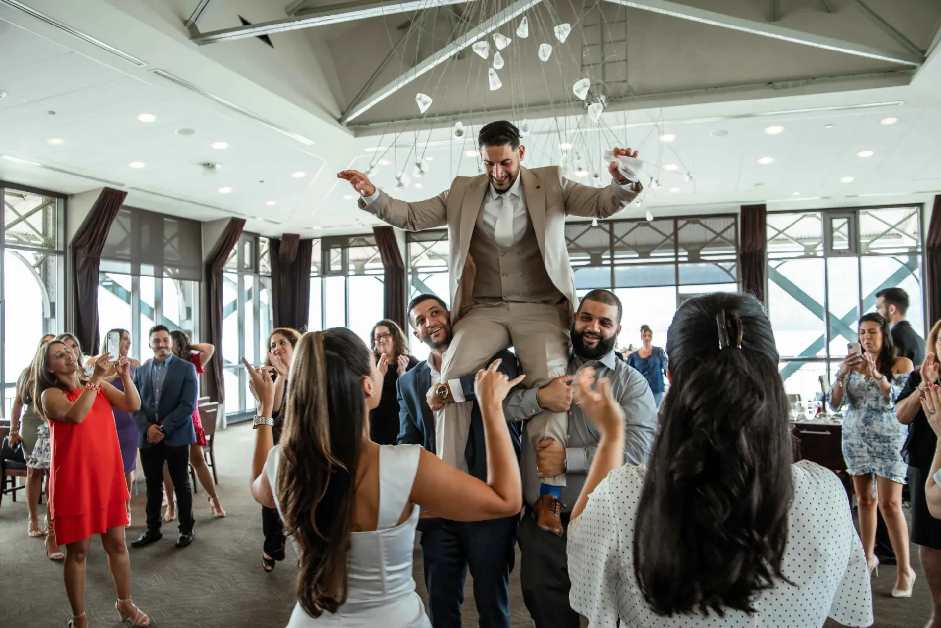 A man is being lifted in the air by a group of people at a wedding reception.