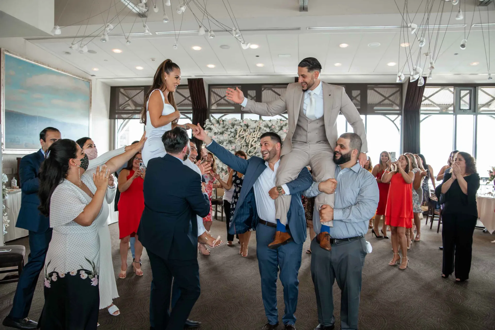 A man is being lifted in the air by a group of people at a wedding reception.