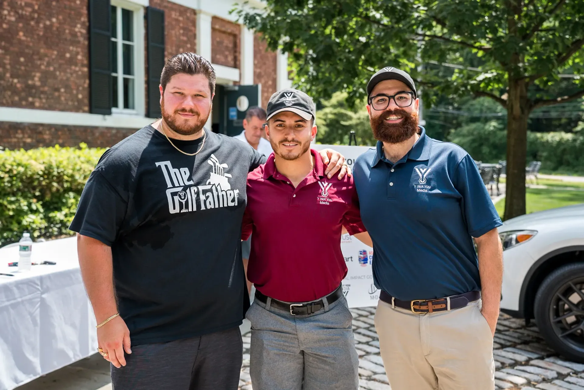 Three men are posing for a picture in front of a white car.