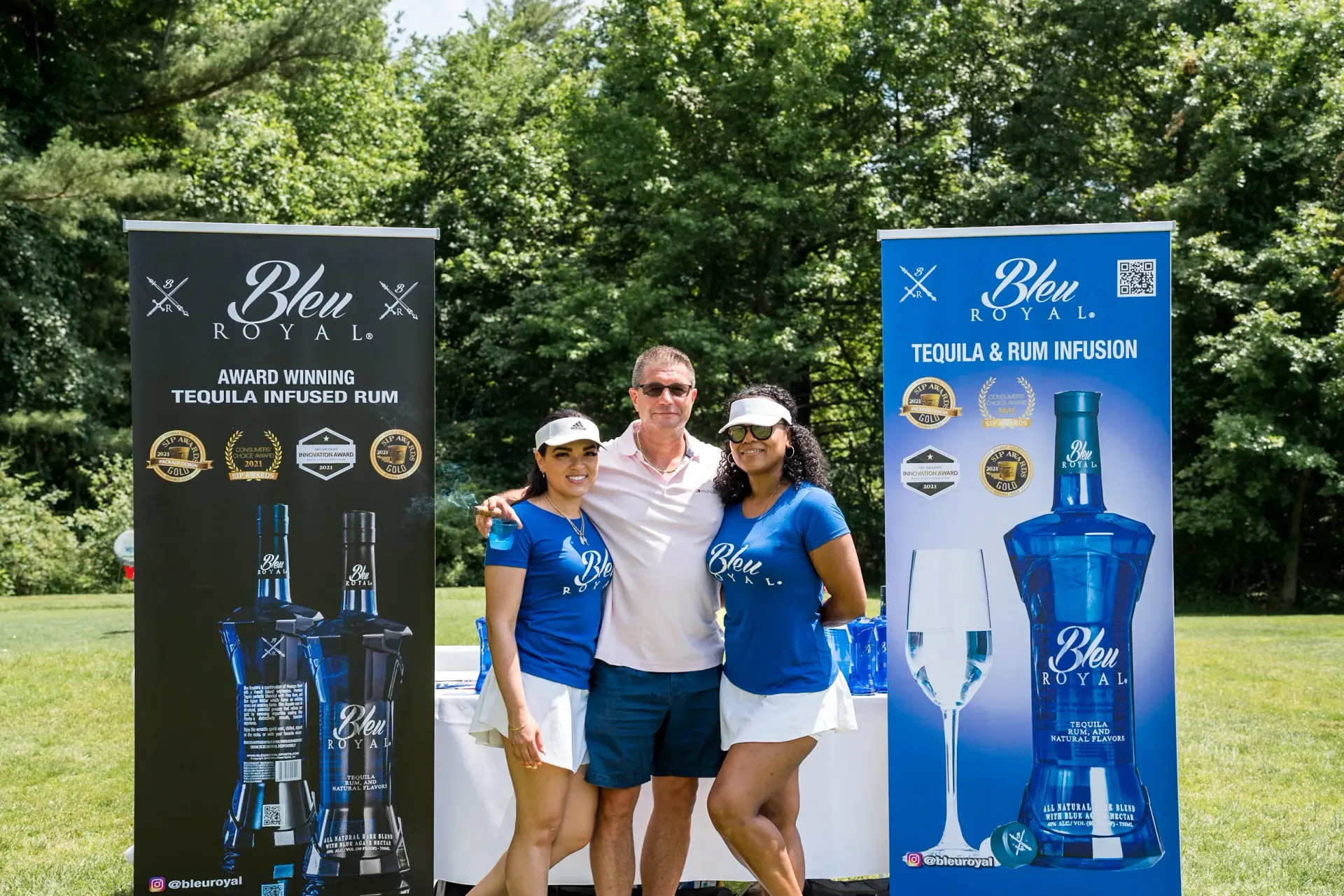 A man and two women are posing for a picture in front of a sign that says ' blue ' on it.