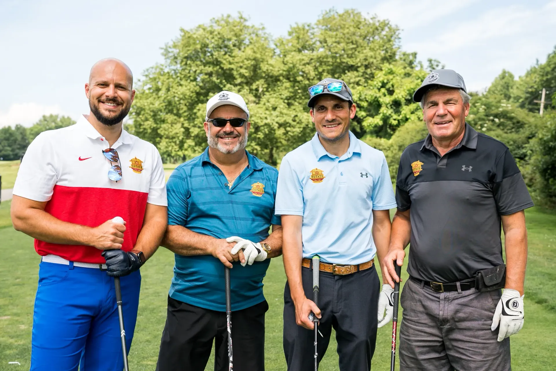 A group of men are standing next to each other on a golf course holding golf clubs.