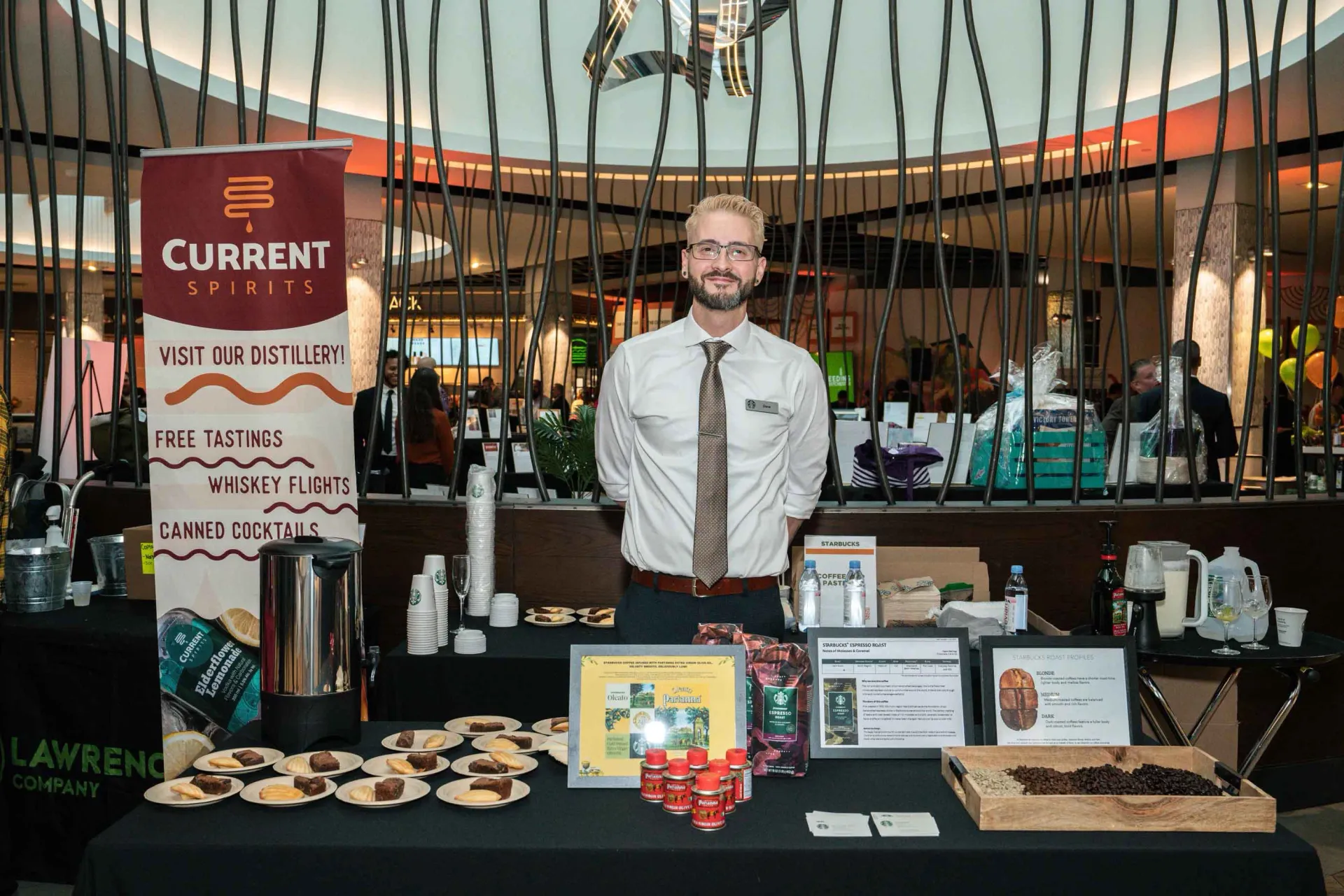 A man is standing in front of a table with a sign that says current spirit.