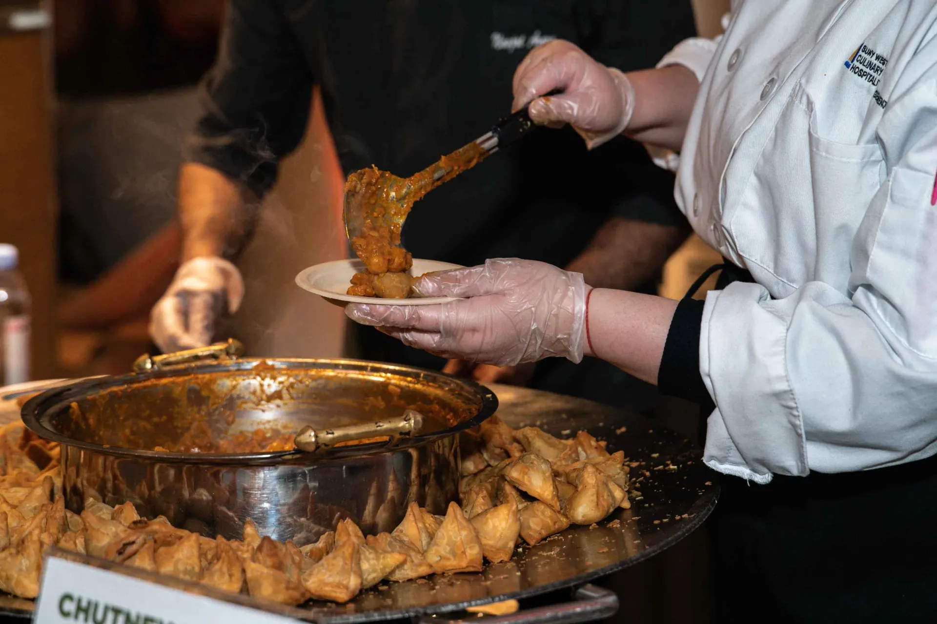 A woman is serving food to a man at a buffet.
