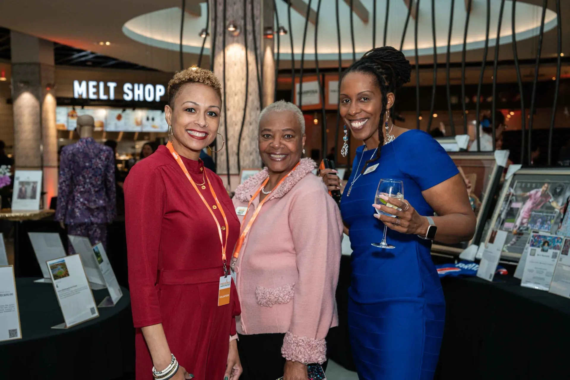 Three women are standing next to each other in a room holding wine glasses.