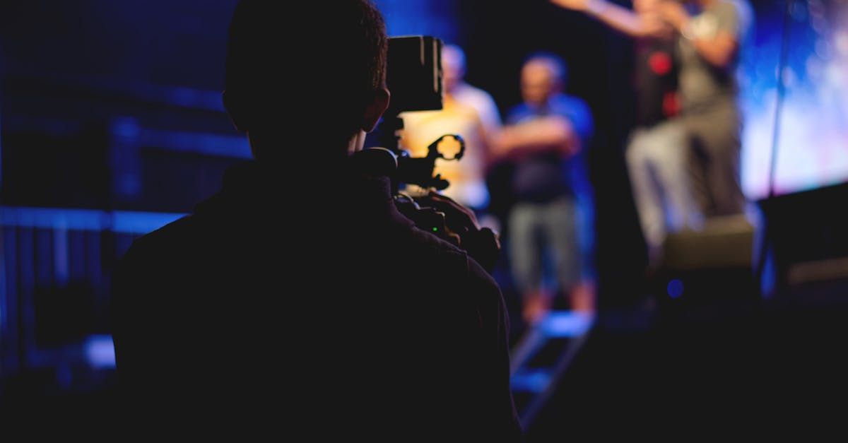 A man is holding a camera in front of a group of people on a stage.