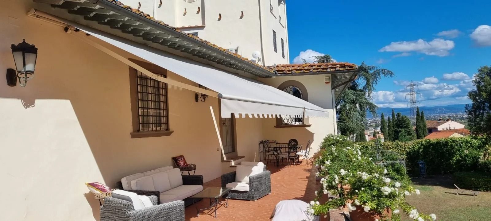 Patio con posti a sedere sotto una tenda da sole, con vista sulla valle nelle giornate di sole.