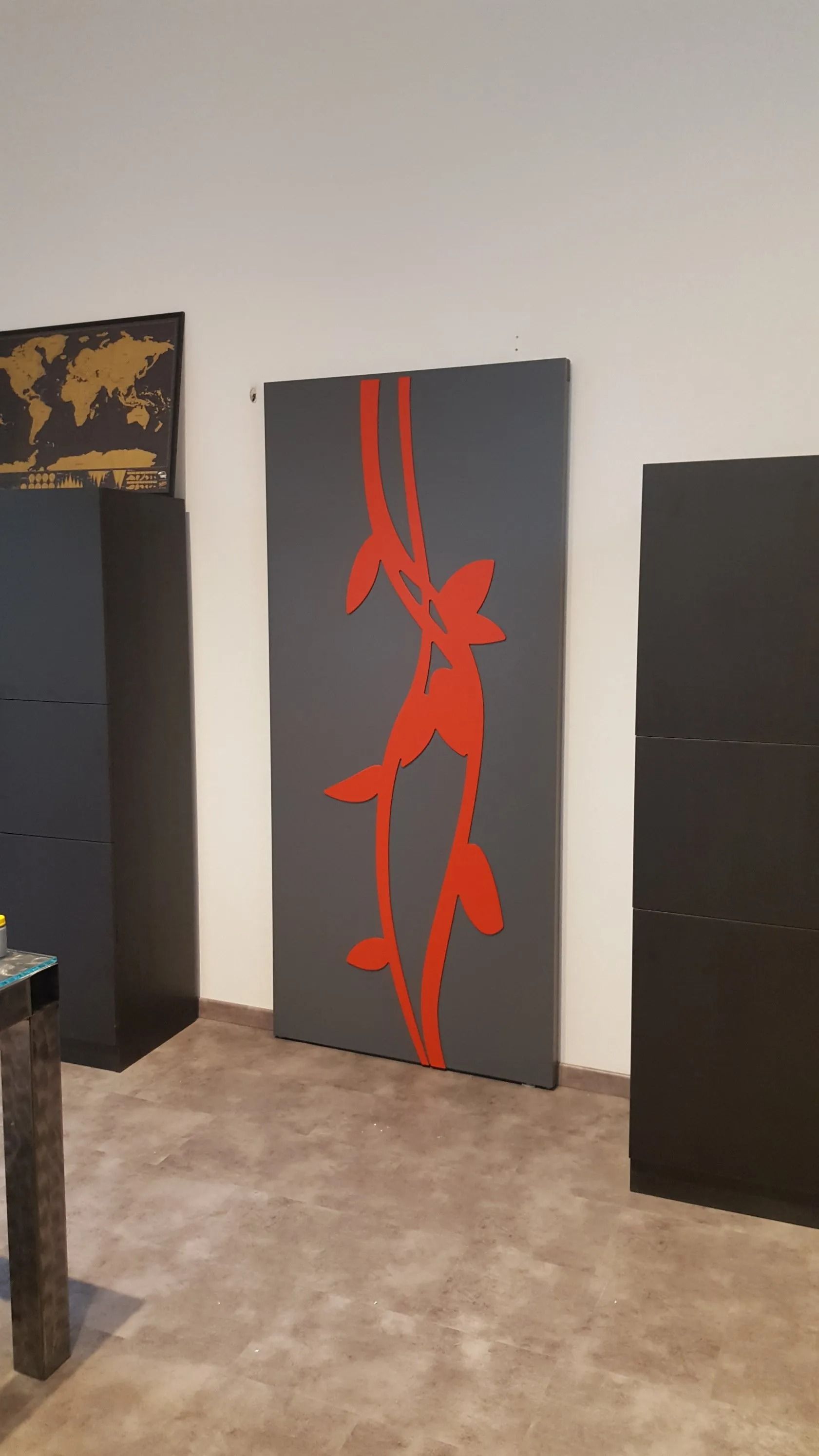 Figure astratte rosse su una tela grigia. L'opera d'arte è collocata al centro di una stanza con mobili e quadri neri.