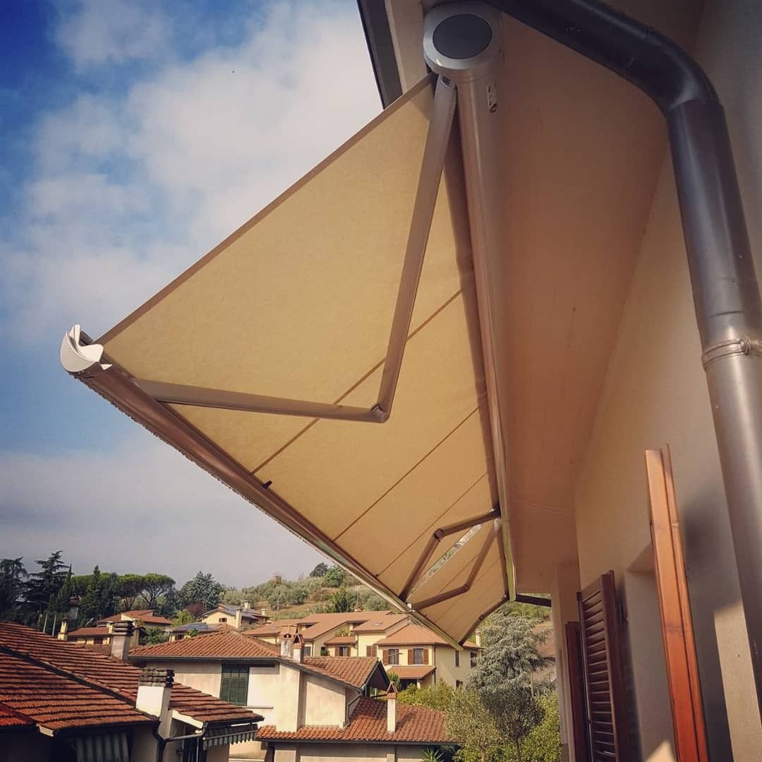 Uomo in abito scozzese blu con in mano un ombrello, che si sistema gli occhiali rotondi e guarda in alto.