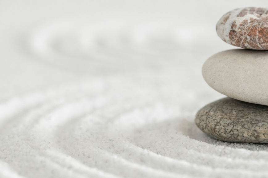 Pila de tres piedras sobre arena blanca, con patrones circulares rastrillados.