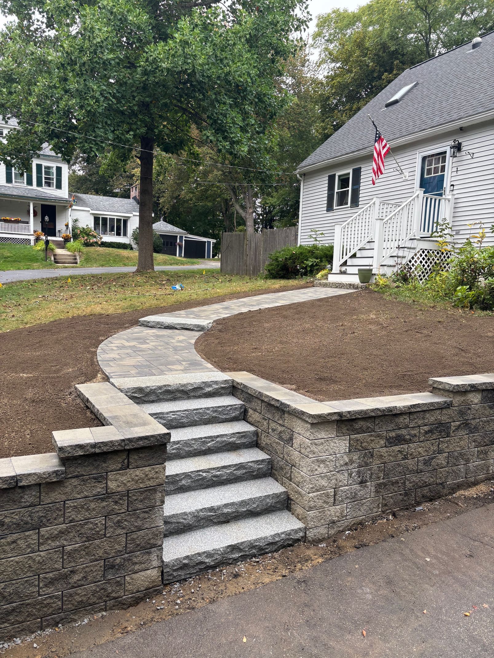 Stone steps and walkway leading to a white house with an American flag.