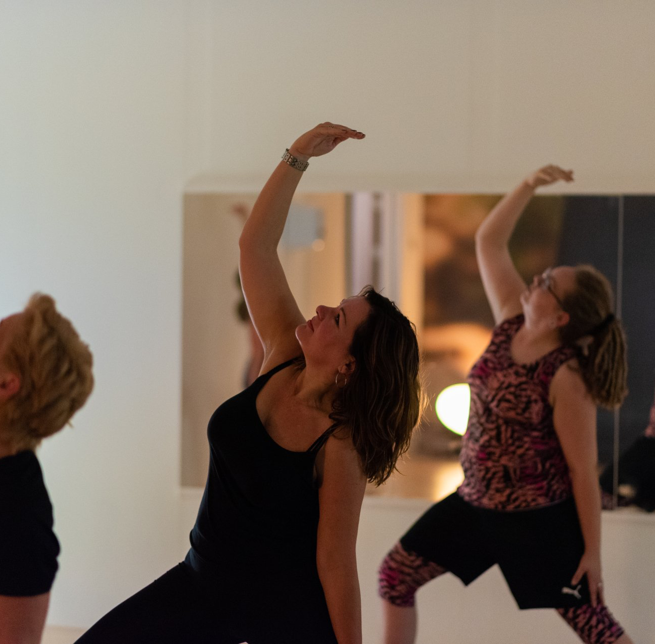 Drie vrouwen beoefenen yoga voor een spiegel