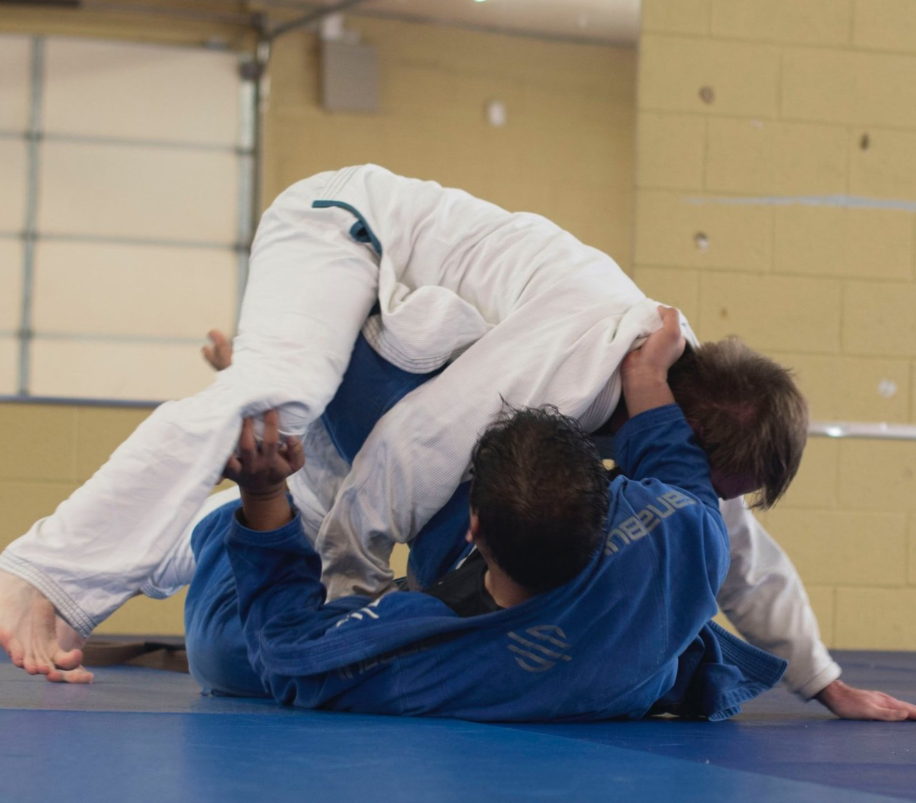 Twee mannen worstelen op een mat in een sportschool.