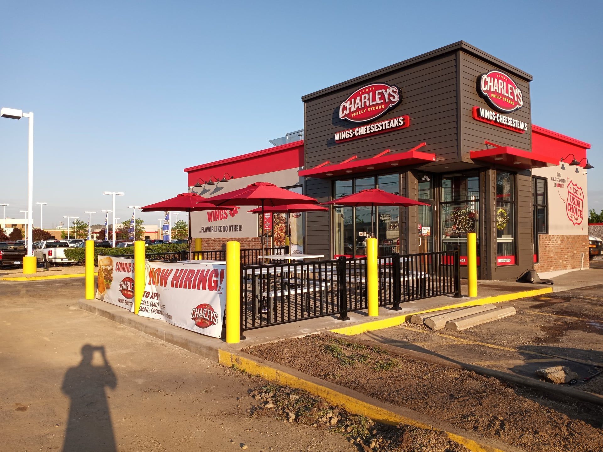 A fast food restaurant with umbrellas and tables in a parking lot.