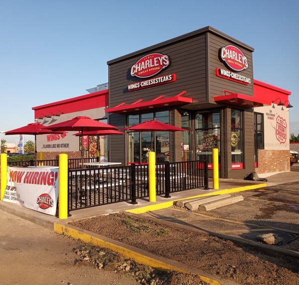 The outside of a charley 's restaurant with red umbrellas