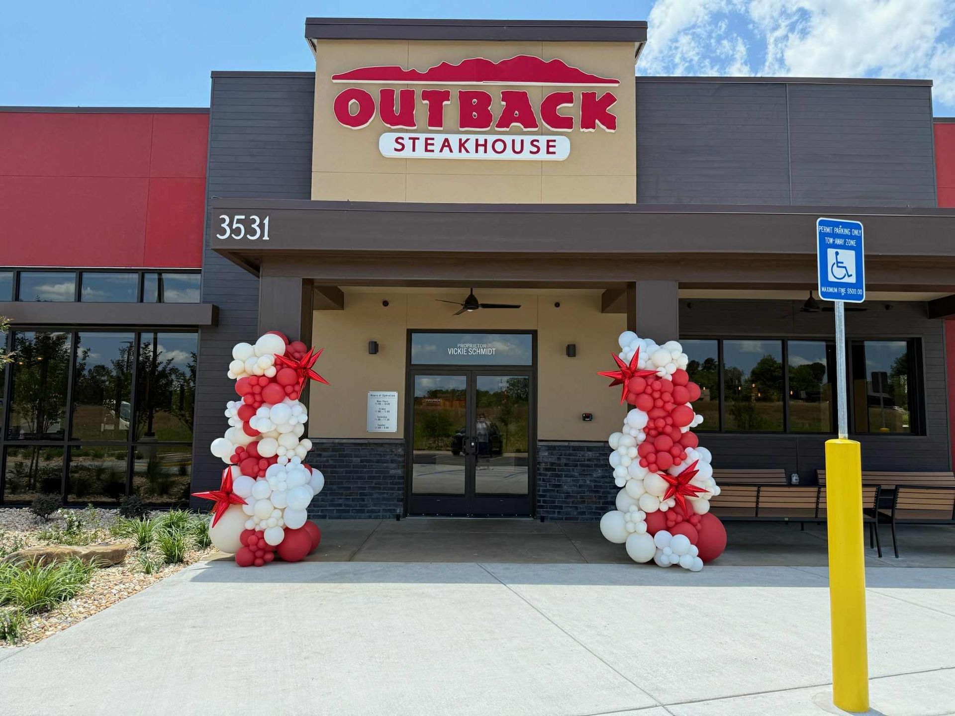 Outback Steakhouse entrance with red and white balloon columns. Accessible parking sign.