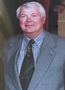 A man with a beard and glasses is wearing a suit and tie.