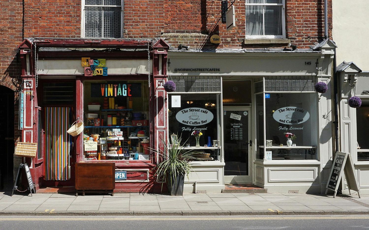 Two small adjacent storefronts with brick upper floors and large glass display windows along a sidewalk.