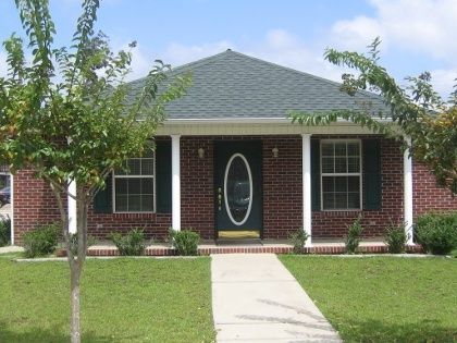 The Holloway Agency Office. A one-story brick house with a dark roof, white pillars, a center oval-window door