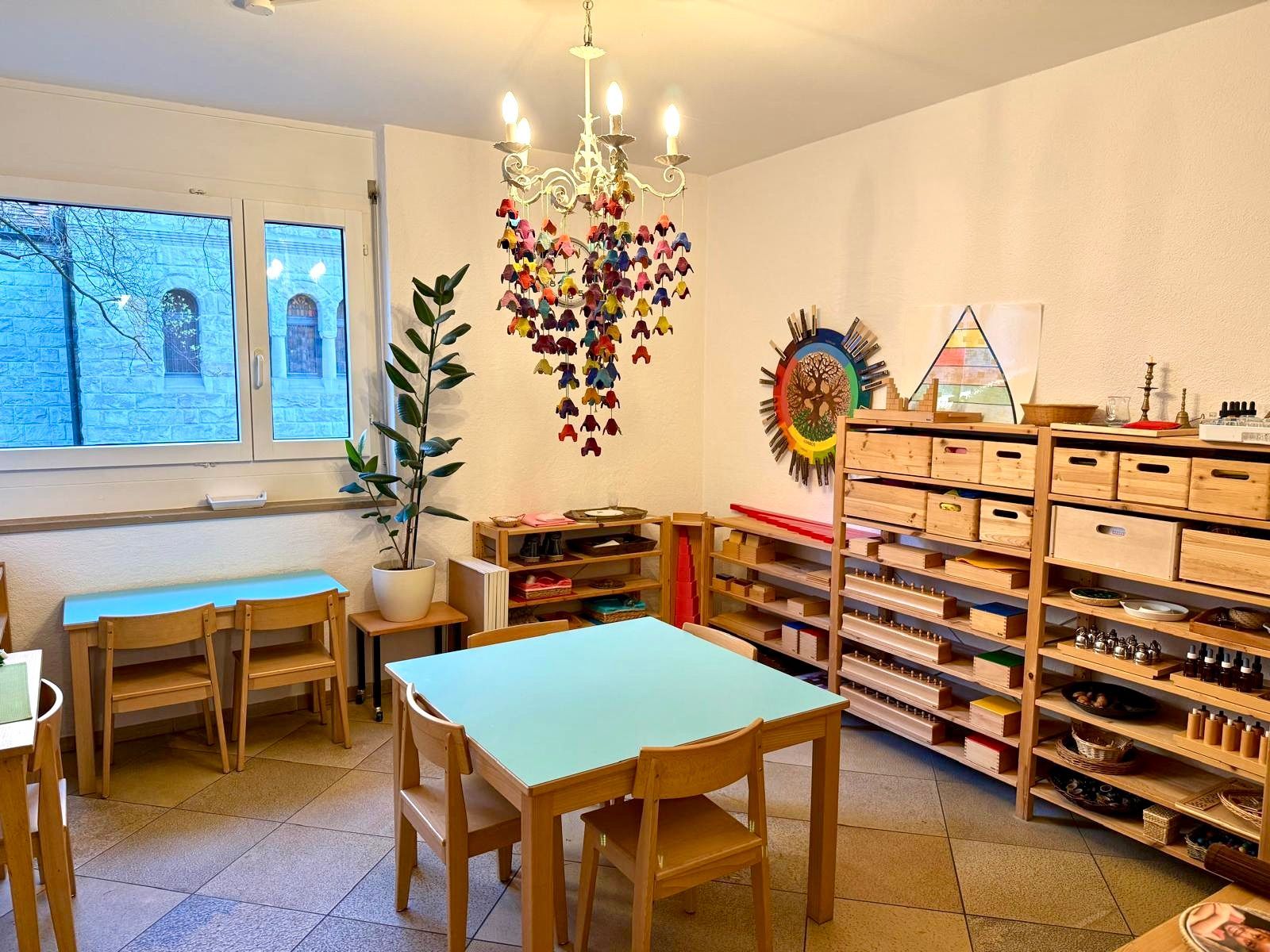 A room with tables and chairs and a chandelier hanging from the ceiling.