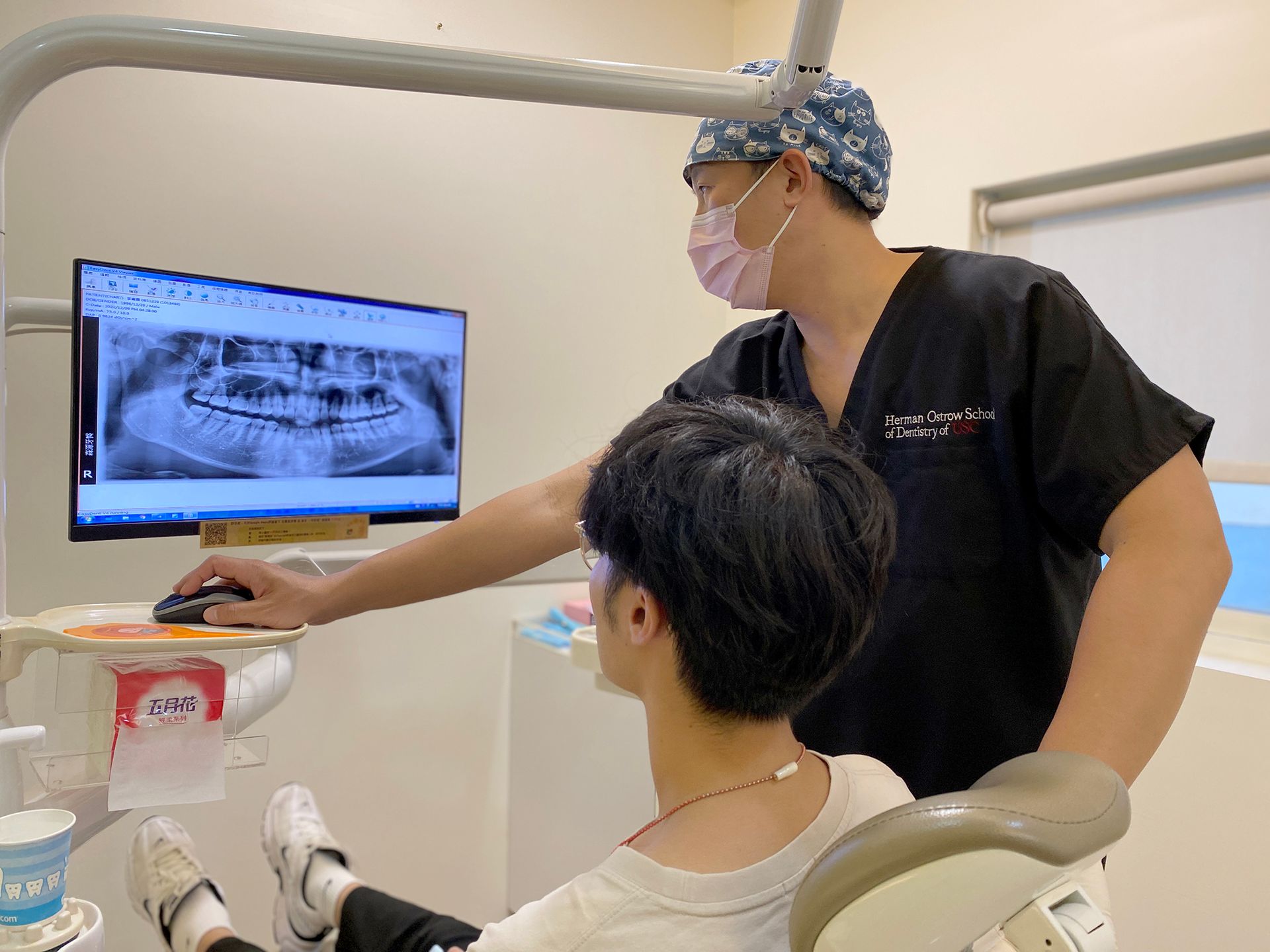 A dentist is looking at a patient 's teeth on a computer screen.