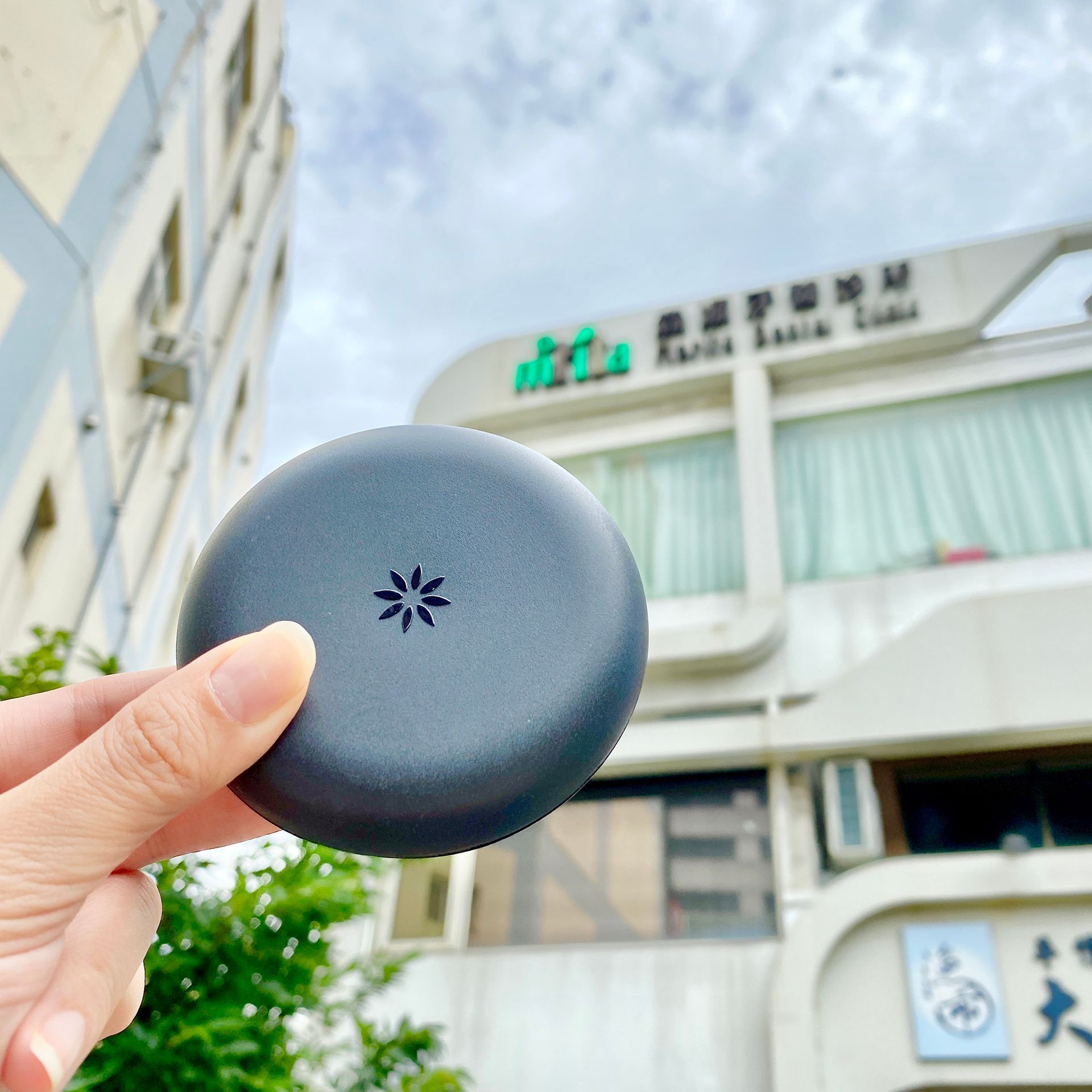 A person is holding a round object in front of a building