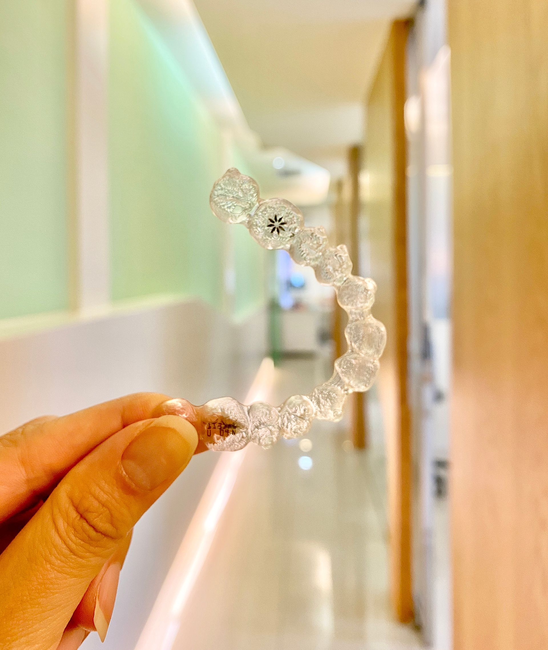 A person is holding a clear ring in their hand in a hallway.
