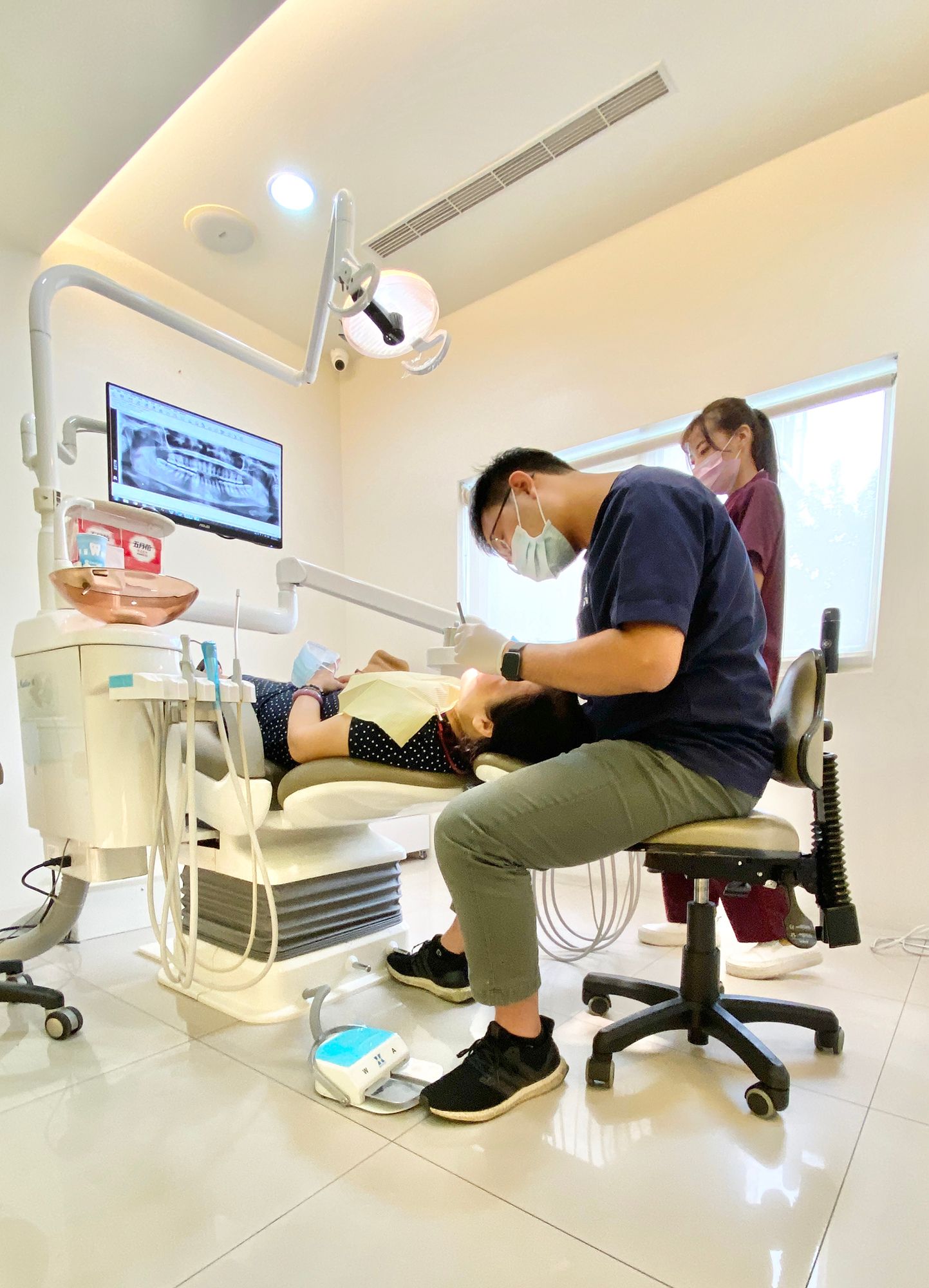 A dentist is examining a patient 's teeth in a dental office.