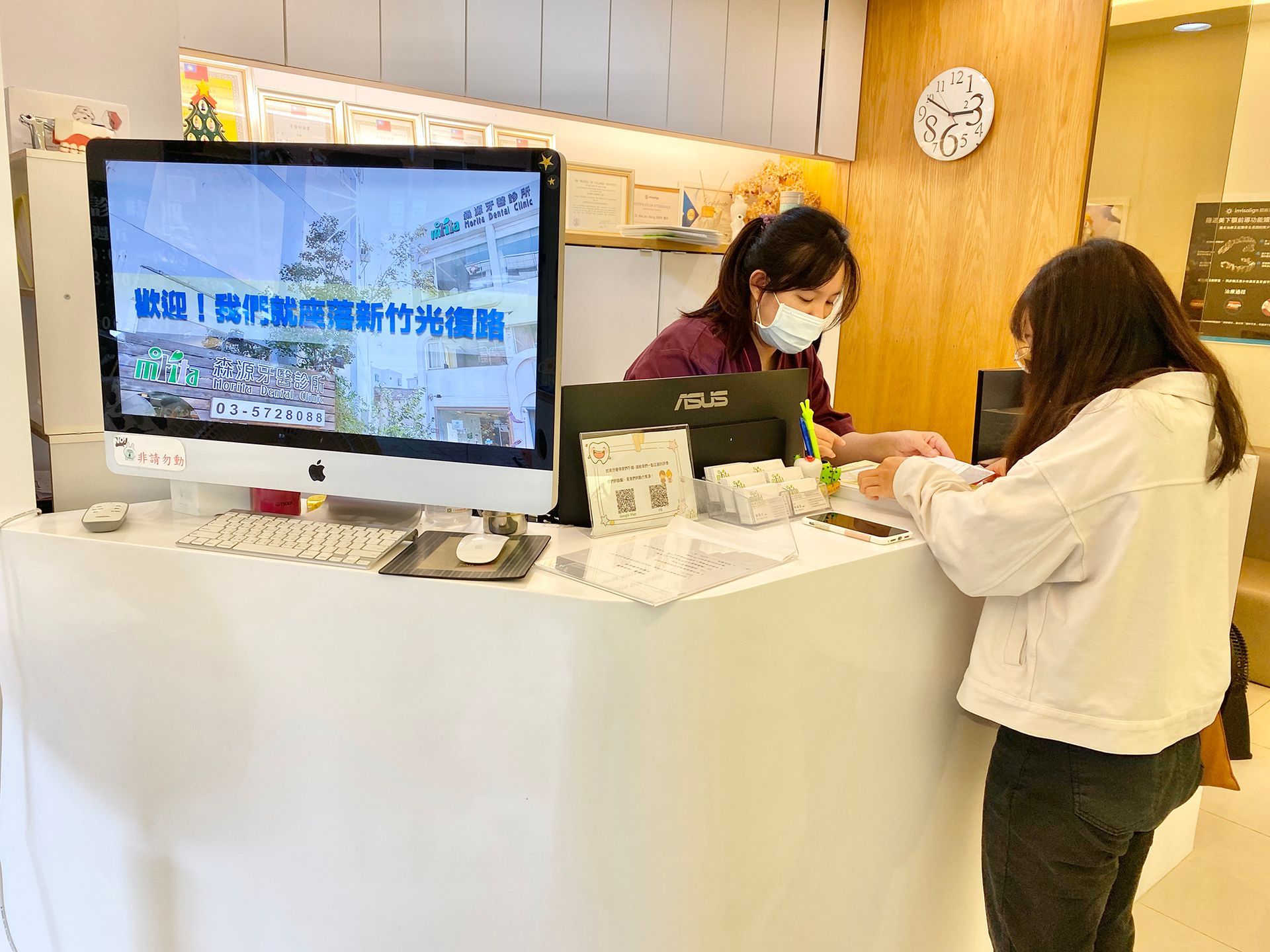 A woman is standing at a counter in front of a computer monitor.