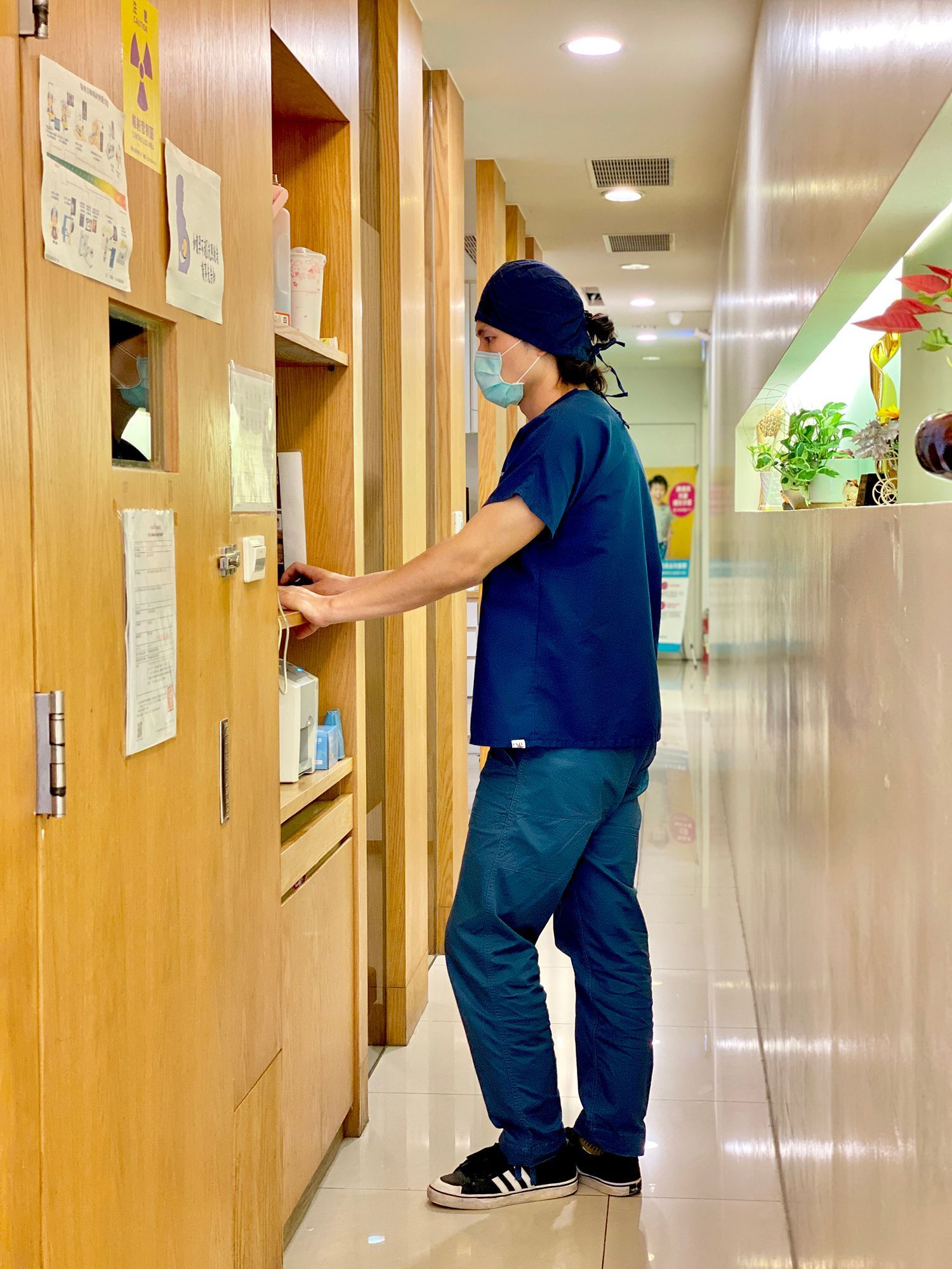 A man wearing a mask is opening a door in a hallway.